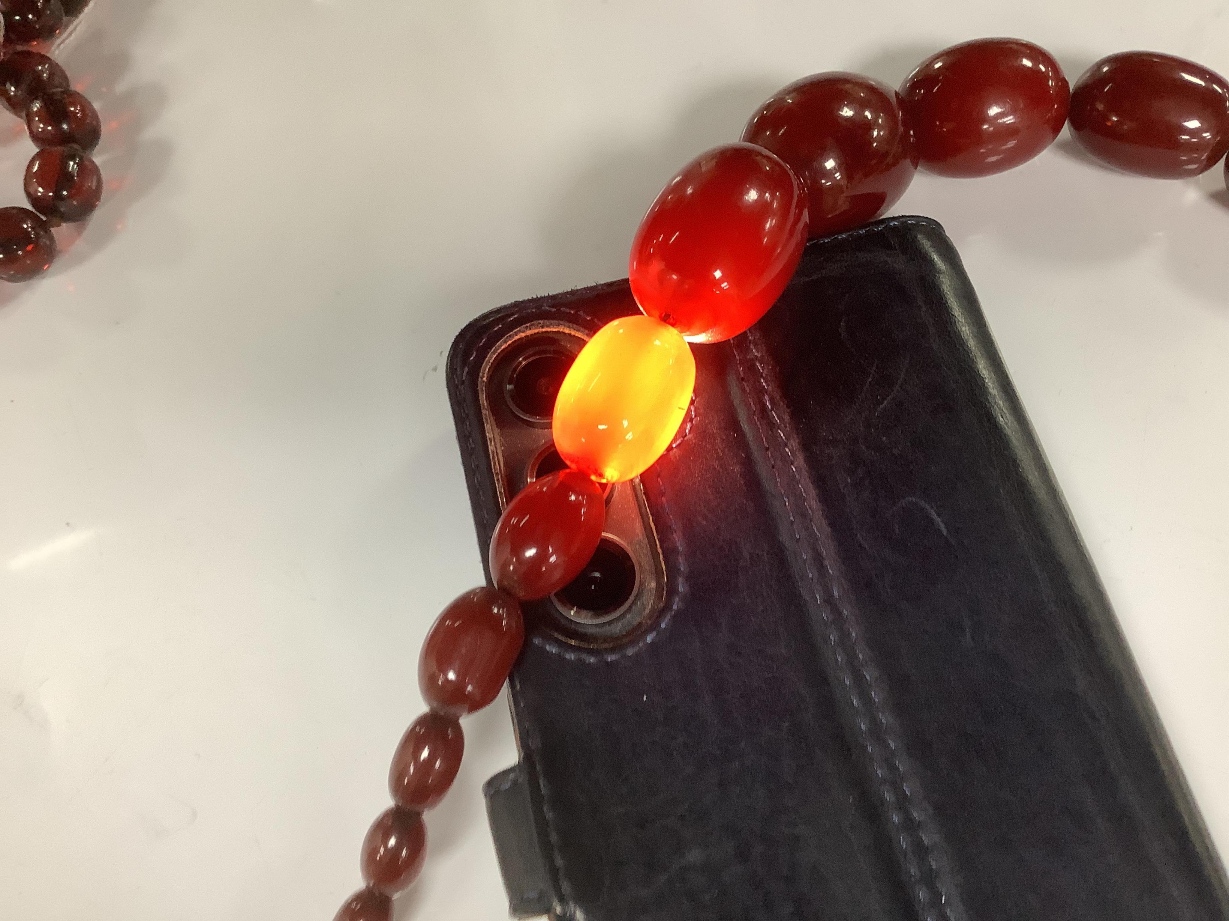 Two single strand simulated cherry amber bead necklaces, including one graduated string, 38cm, gross weight 173 grams. Condition - fair